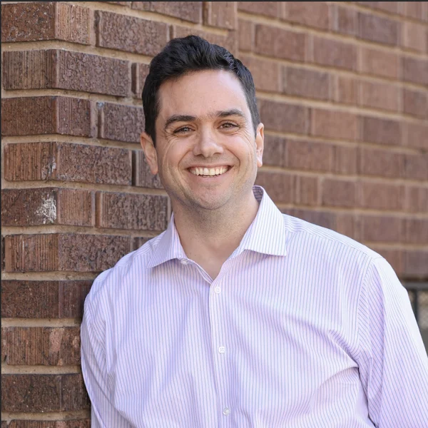 Aaron Barker smiling against a brick wall