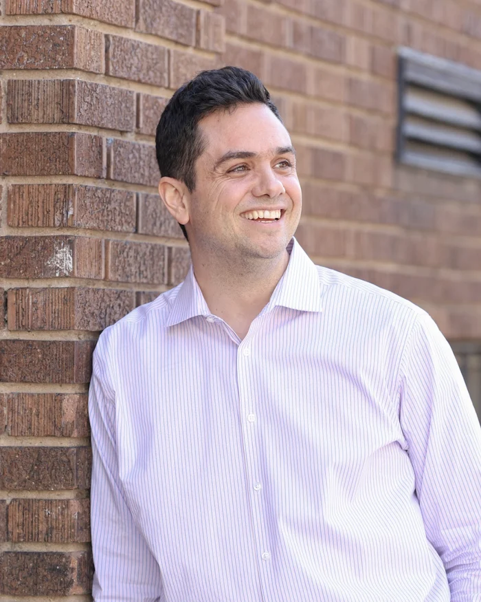 Aaron Barker laughing, leaning on a brick wall