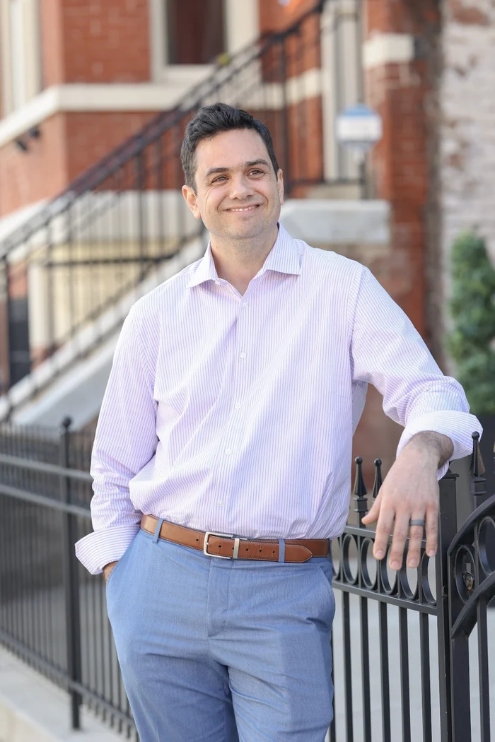 Aaron Barker leaning on an iron fence on a brick street