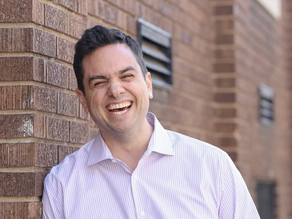 Aaron laughing against a brick wall